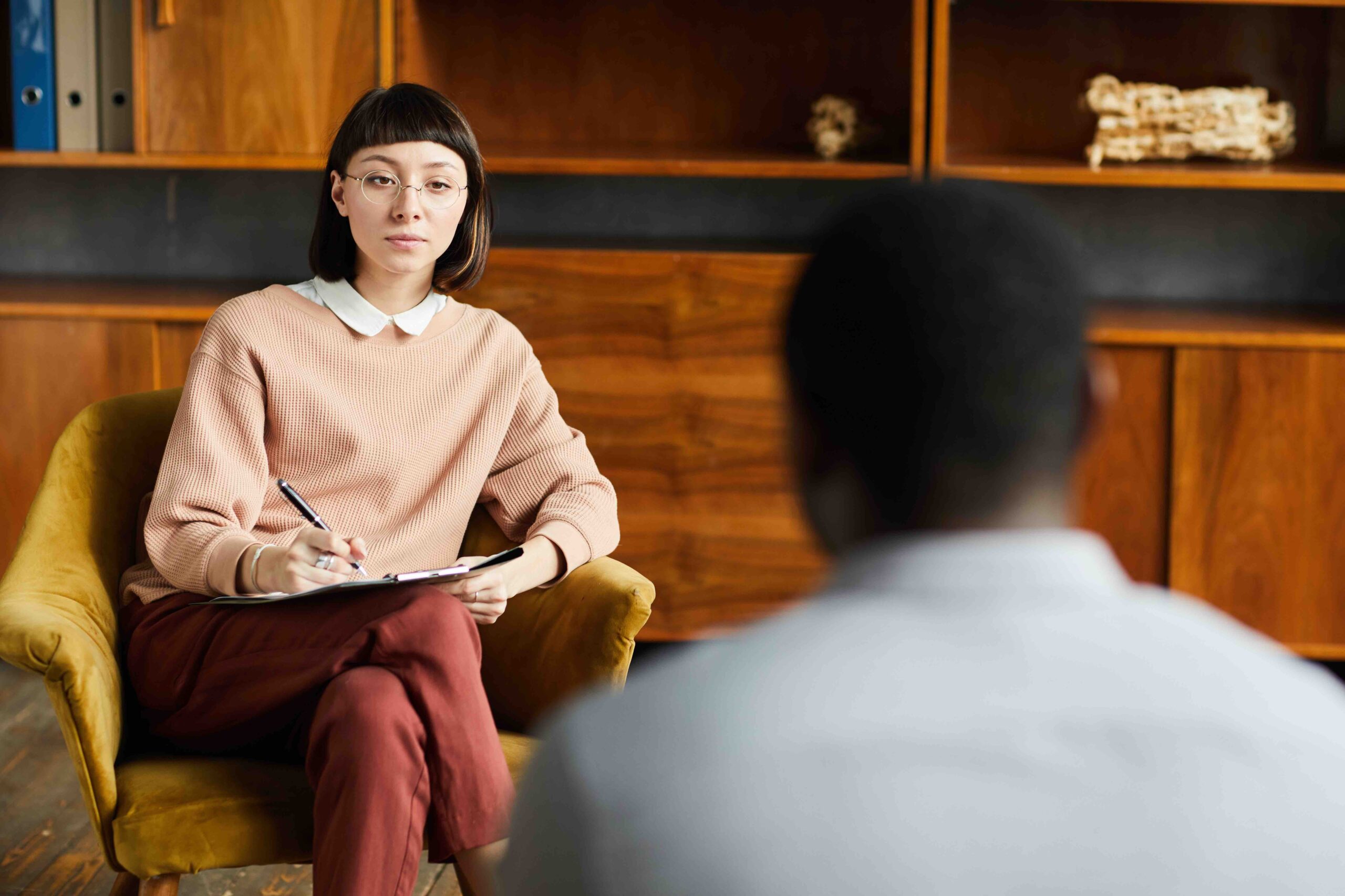 Young woman sitting on armchair during her psychology therapy and talking to psychologist