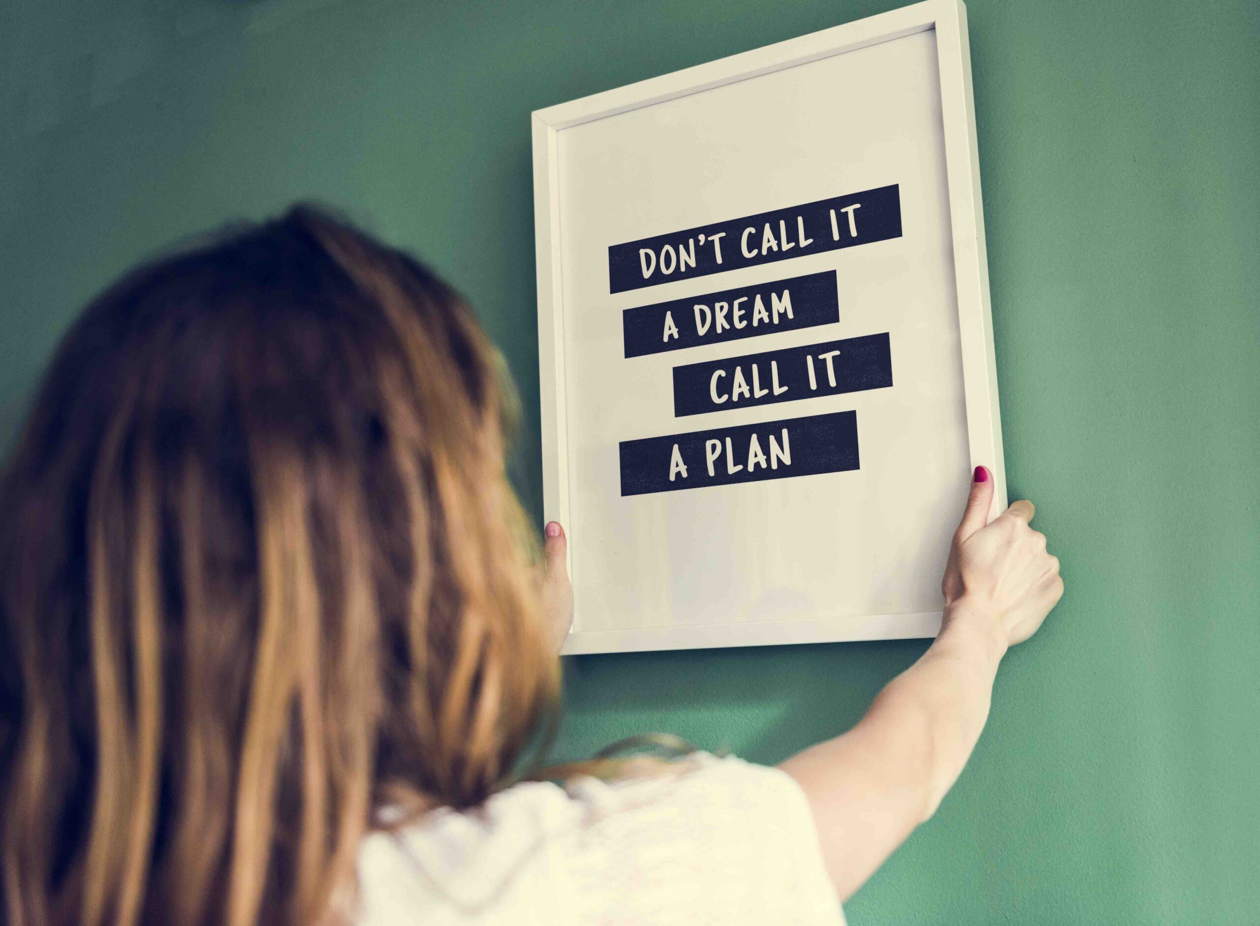 Girl hanging a frame on a green wall