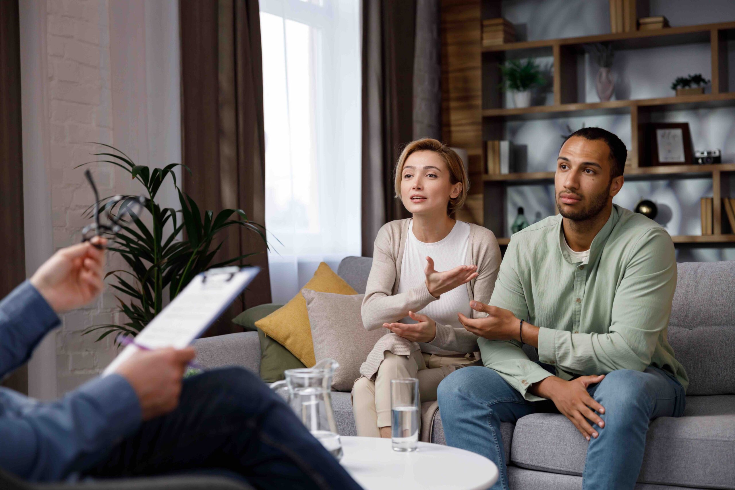 Multiracial quarrel between husband and wife at a session with a psychotherapist. A visit to a family psychologist for a married couple. A doctor consults an unhappy married couple. Help psychologist